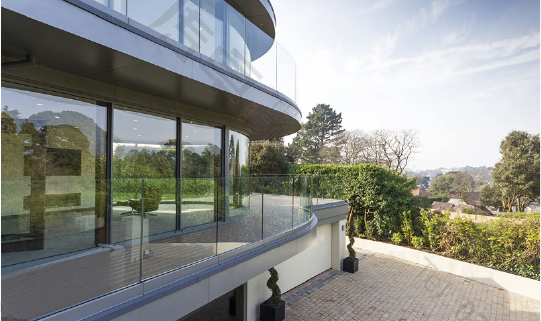 Curved residential facade with aluminium-framed glazing and glass balustrades